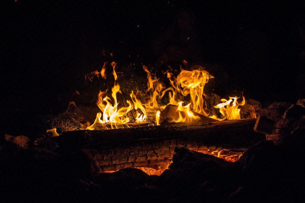 A bunch of burning logs cast light into darkness